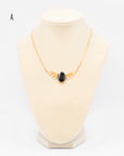 Gold-fill necklace with central onyx stone and wing-like leaf shaped design with a 16 inch gold fill chain on a jewelry bust