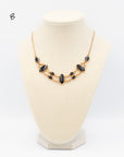 Gold-fill necklace featuring nine various sized, polished onyx stones connected via gold fill links on a jewelry bust