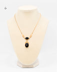 Gold-fill necklace with two onyx stones in a drop-style design with gold-fill leaf accents and a central rhinestone, displayed on a jewelry bust.