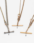 Close up of 3 necklaces labeled E, F, G made from Victorian-era men’s watch chains with antique T-bars and dog clips. Authentic 100+ year-old pieces made from sustainable vintage chains laying flat on a white background.