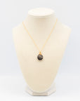 Single vintage black cloisonné ladybug necklace displayed on a white jewelry bust