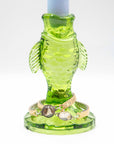 Green glass fish-shaped candle holder holding vintage bracelets with hand-painted glass pendants on a white background