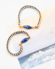 Two gold and silver beaded bracelets with lapis lazuli stones on a white surface.