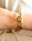 Close-up of a wrist wearing a vintage bracelet with a lemon quartz stone against a neutral background