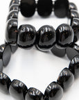 Close-up of two black onyx beaded bracelets stacked together, highlighting the glossy polished surface of the chunky stone beads.