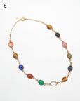 A gold-filled necklace featuring multiple oval scarab gemstone beads in various colors including brown, pink, blue, red, green, and clear, displayed on a white background.