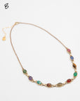 Scarab gemstone necklace with nine multicolor carved stone beetles arranged flat against a white background.