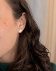 Close-up of a woman wearing silver fan-shaped earrings.