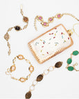 Five gold-fill vintage bracelets with cameos, carved peking glass, carved tiger's eye, pink glass and agate on a white background around a pop-tart holiday ornament