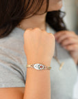 Woman in a gray tee wearing the Winter Bloom enameled flower watch band bracelet