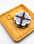 Flower-shaped wooden press keychain with layered pages on a wooden tray