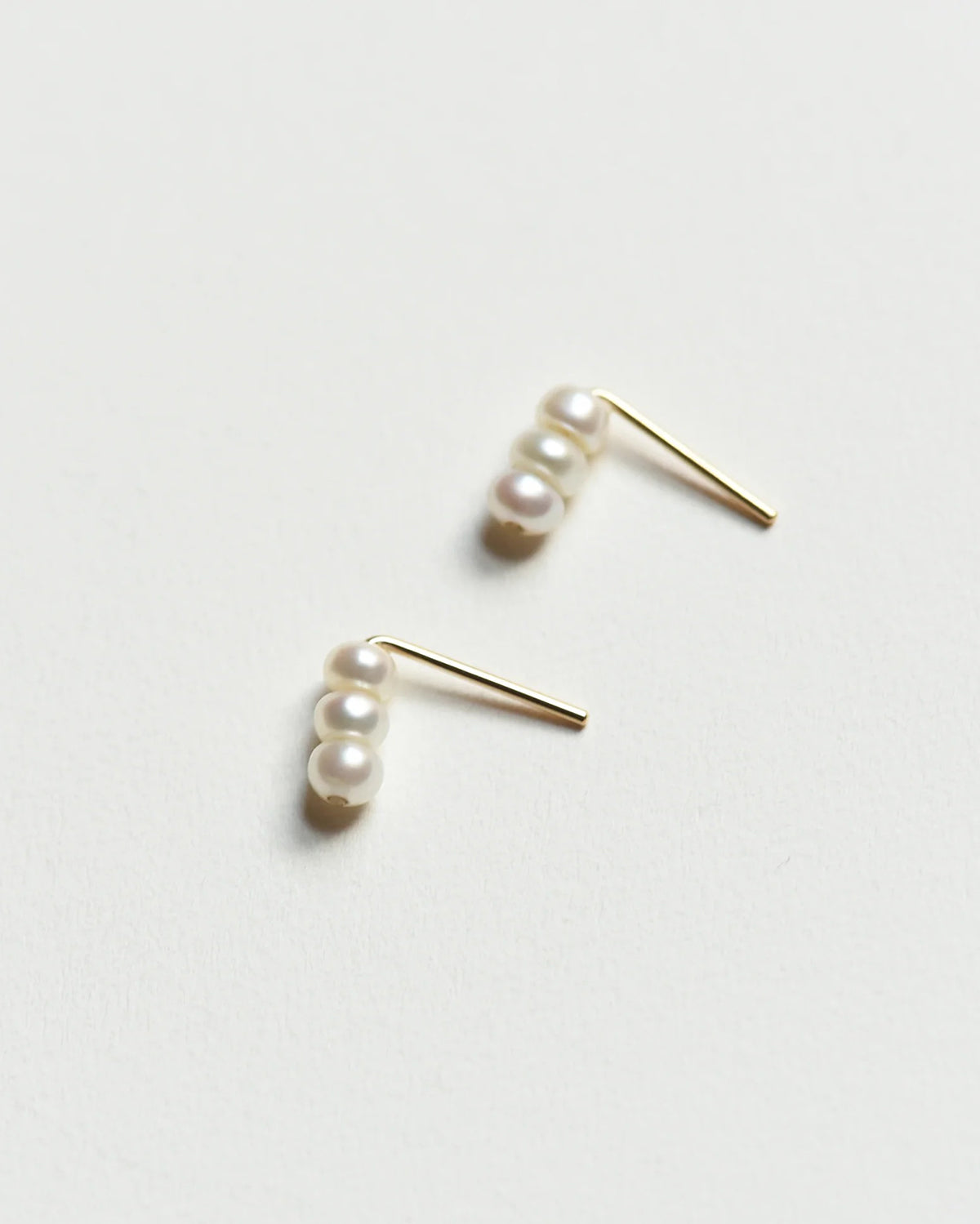 Pair of 8.6.4 freshwater pearl stud earrings on white background.