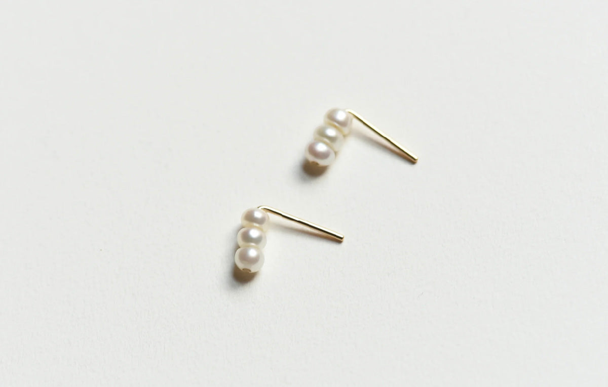 Pair of 8.6.4 freshwater pearl stud earrings on white background.