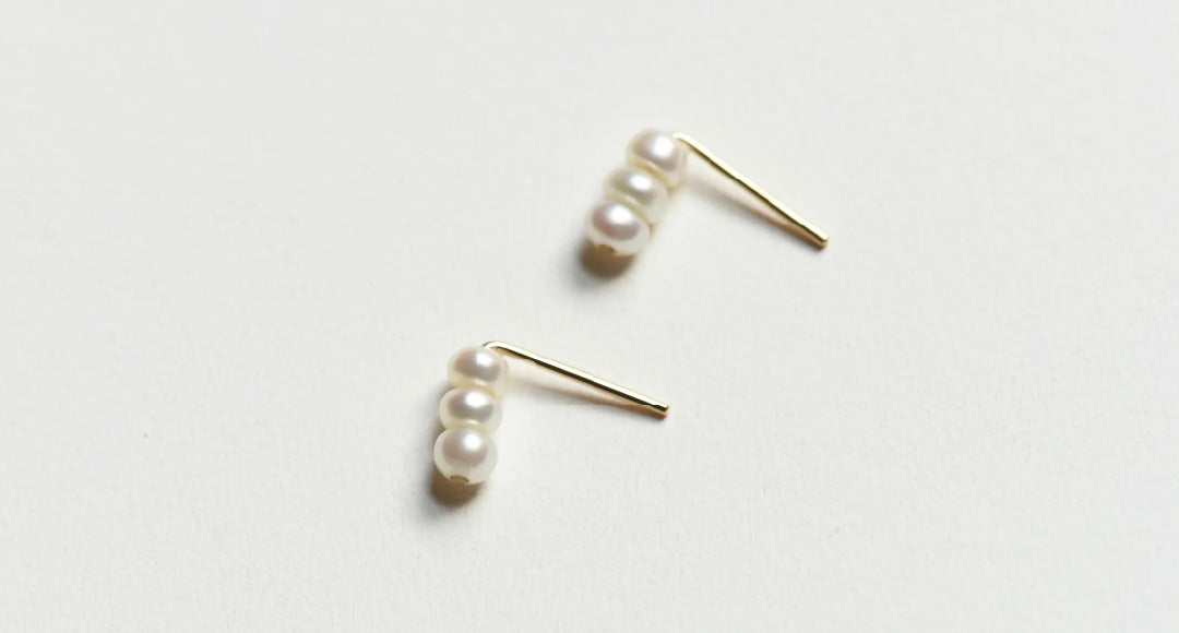Pair of 8.6.4 freshwater pearl stud earrings on white background.