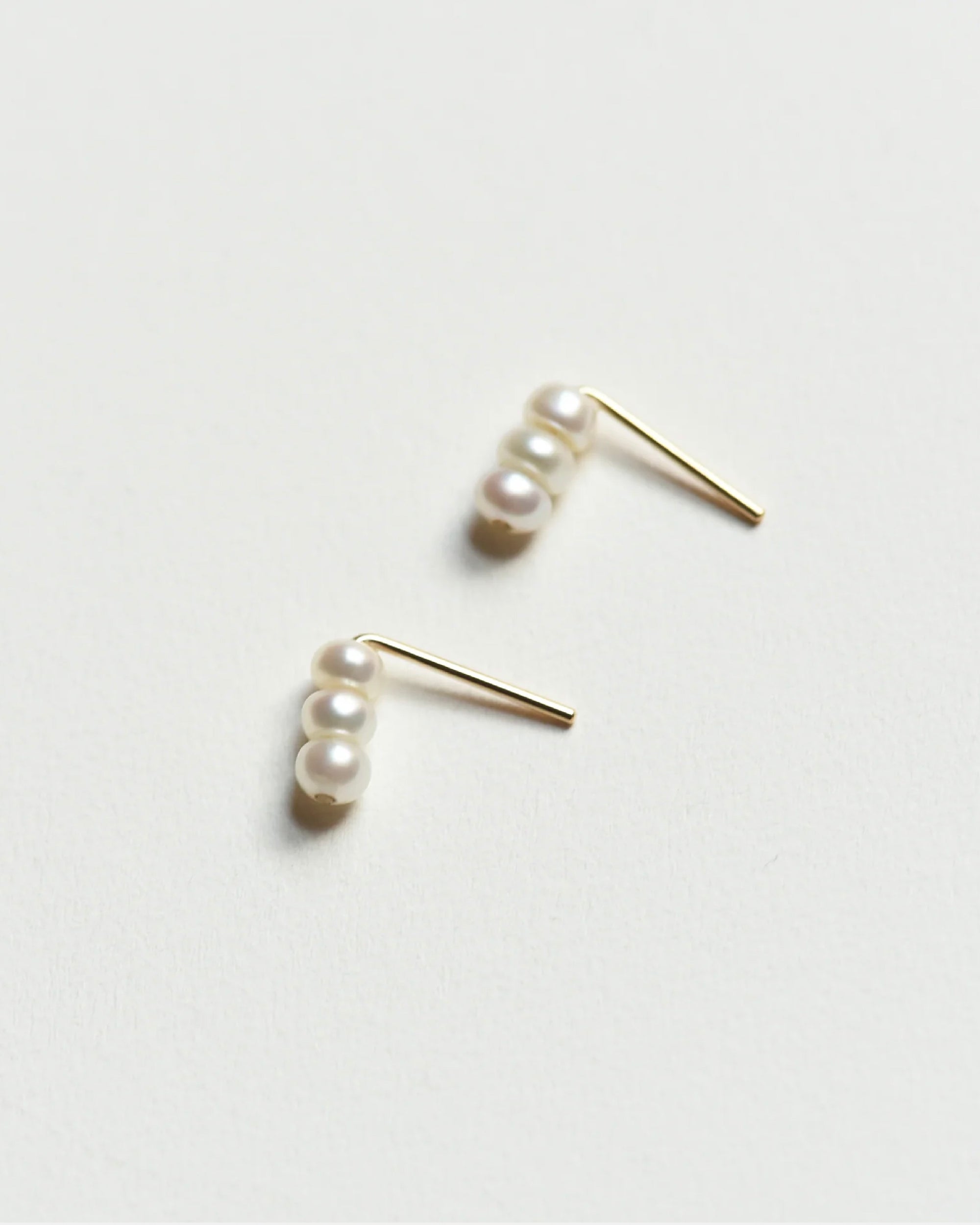 Pair of 8.6.4 freshwater pearl stud earrings on white background.