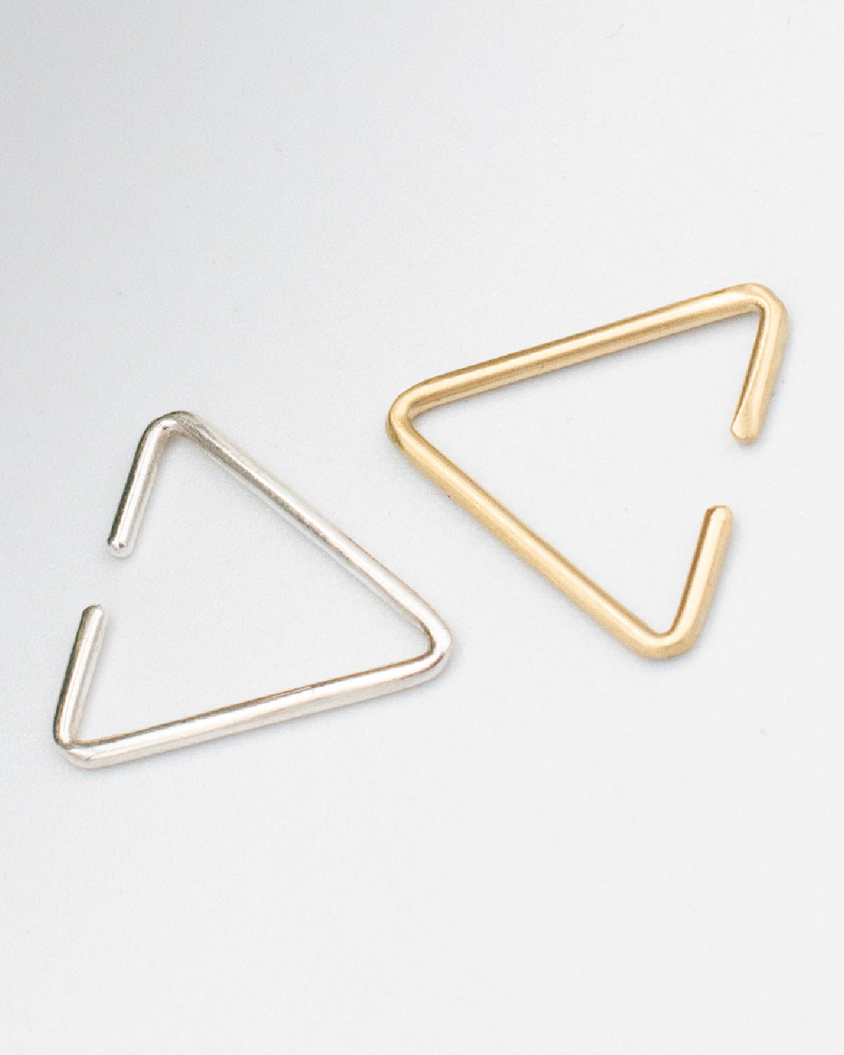 Close up of 8.6.4 handmade triangle ear cuff in brass and silver. 