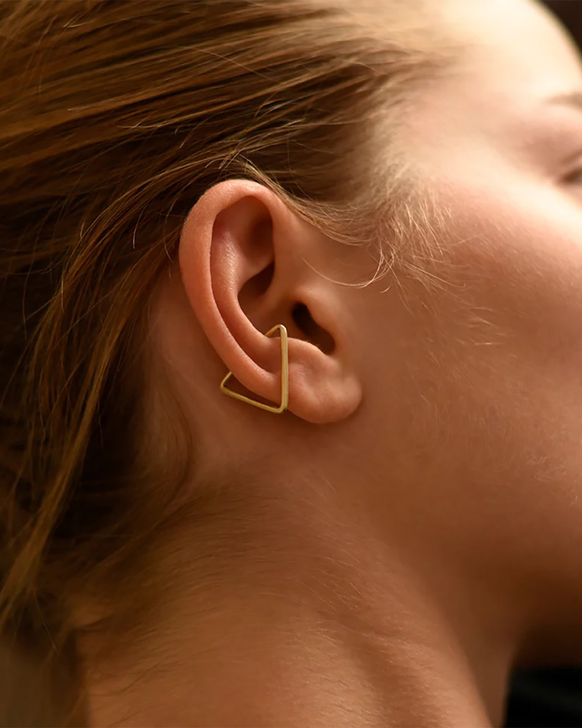 Close up of woman wearing 8.6.4 handmade triangle ear cuff in brass.
