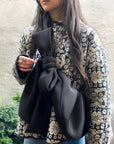 Person wearing a black bow crossbody bag with a quilted jacket and jeans