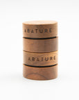 Two stacked Abature wood lip pots engraved with the brand name