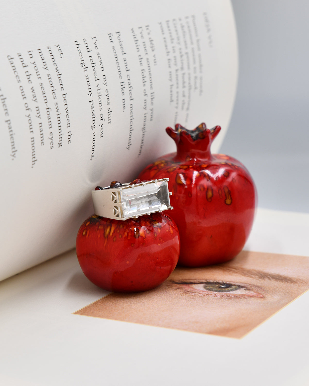 Silver and clear quartz ring on a ceramic pomegranate in the pages of an opened book