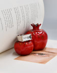 Silver and clear quartz ring on a ceramic pomegranate in the pages of an opened book