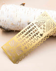 Another Studio brass art deco stencil with alphabet and sunburst cutouts on a birch log