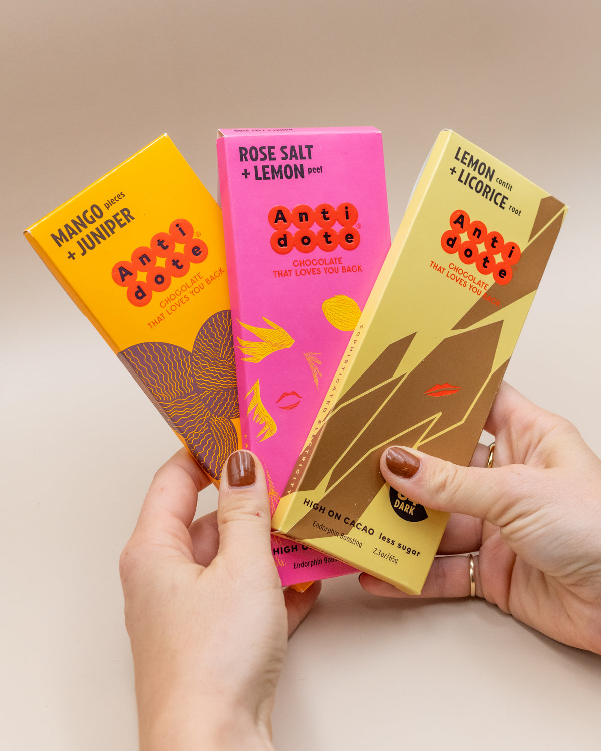 Hands holding Antidote dark chocolate bars in Mango Juniper, Rose Salt Lemon and Lemon Licorice