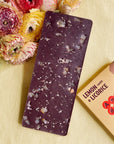 Antidote Lemon and Licorice dark chocolate bar studded with candied lemon, beside flowers