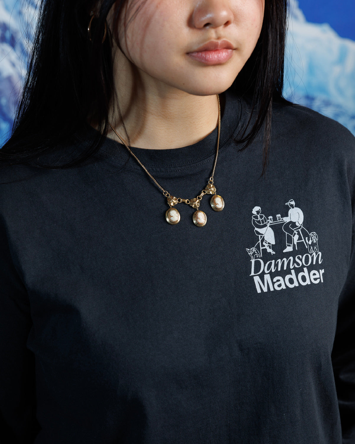 Woman wearing vintage shell cameo necklace with gold floral accents on a black, graphic tshirt