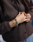 Close up of a person in brown sweater wearing two antique gold-filled scarab stone bracelets with double link settings.