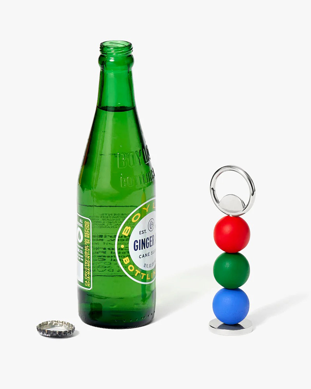 Red, green  blue bottle opener next to a green glass bottle. 