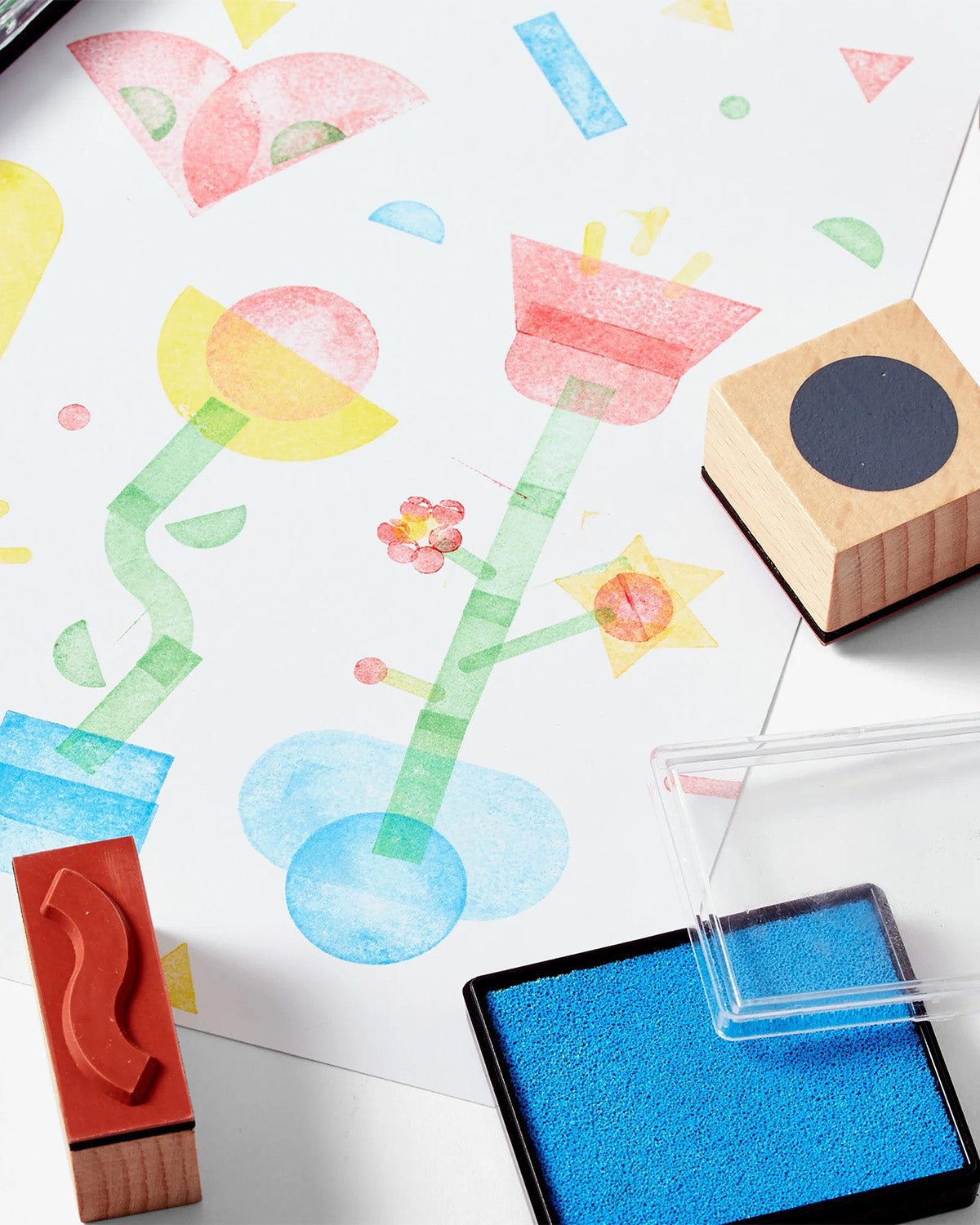 Colorful children's artwork with rubber stamps and ink pad on a white surface