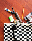 Checkered knit bag with makeup items on a wooden surface