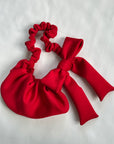 Closeup of a red bow crossbody bag on a gray background