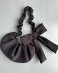 Closeup of a black bow crossbody bag on a gray background