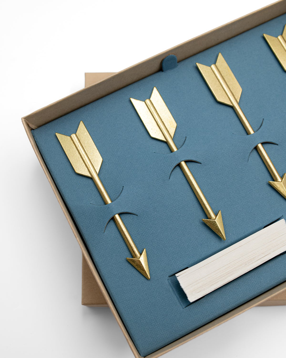Close-up of gold arrow cheese markers nestled in a blue box with paper banners