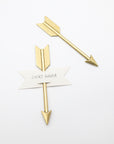 Two gold arrow cheese markers, one holding a paper banner that reads Smoky Gouda