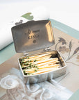 Beehive Handmade Spark a Revolution pewter matchbox open on botanical print magazine showing green-tipped strike-anywhere matches and "No More Kings" engraving inside lid