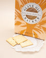 Bella Cucina Olive Oil Cracker box with square crackers on a lace doily