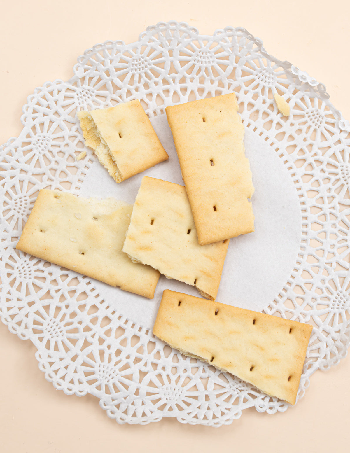 Square olive oil and sea salt crackers on a white lace doily