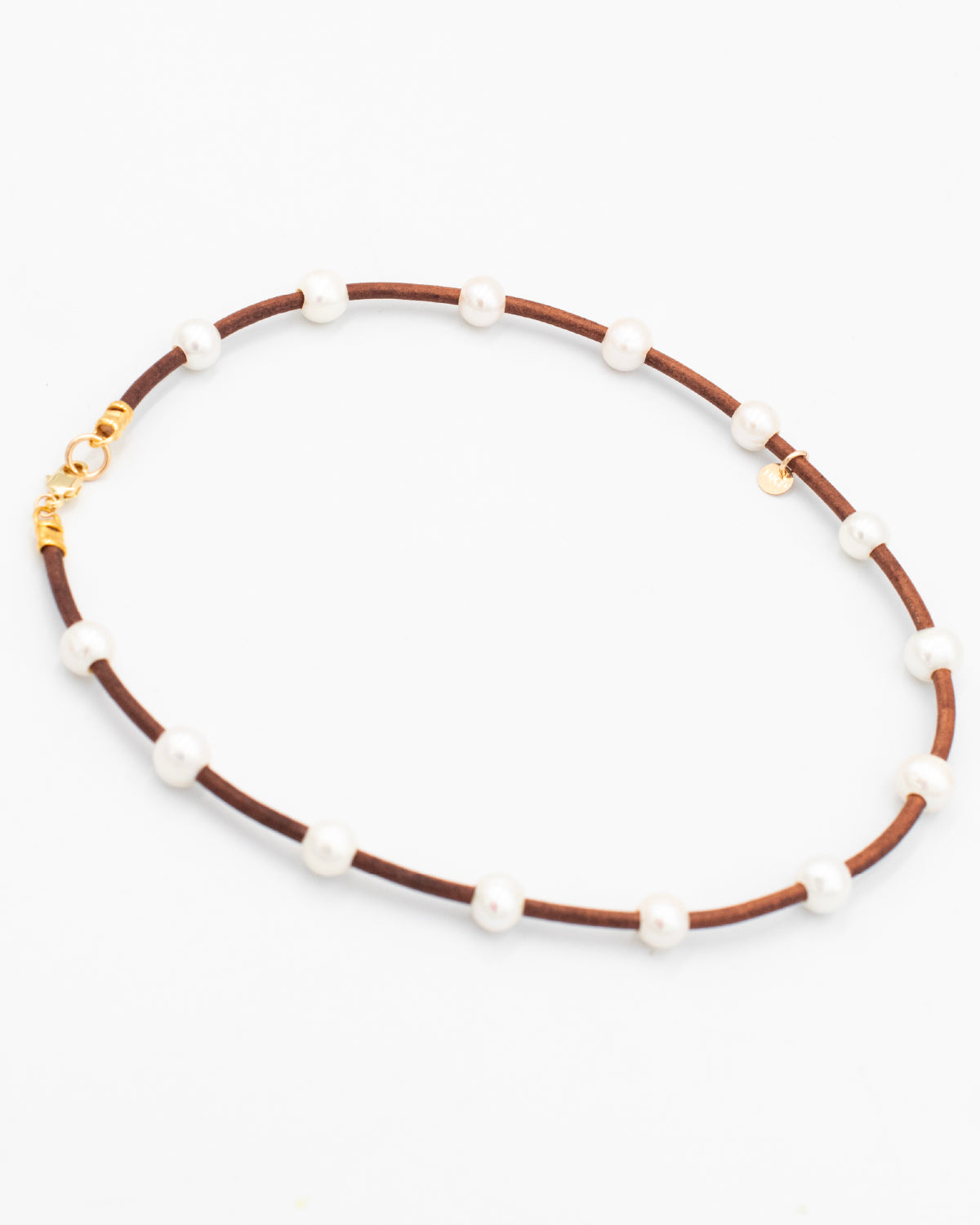 Handmade pearl and leather cord necklace laying flat on a white background