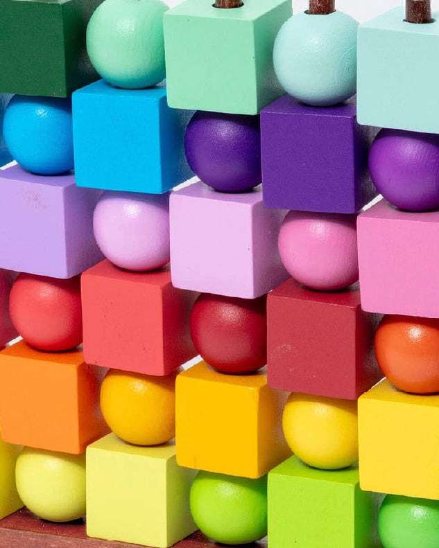 Close-up of the rainbow wooden cubes and balls stacked on the Four in a Row pegs