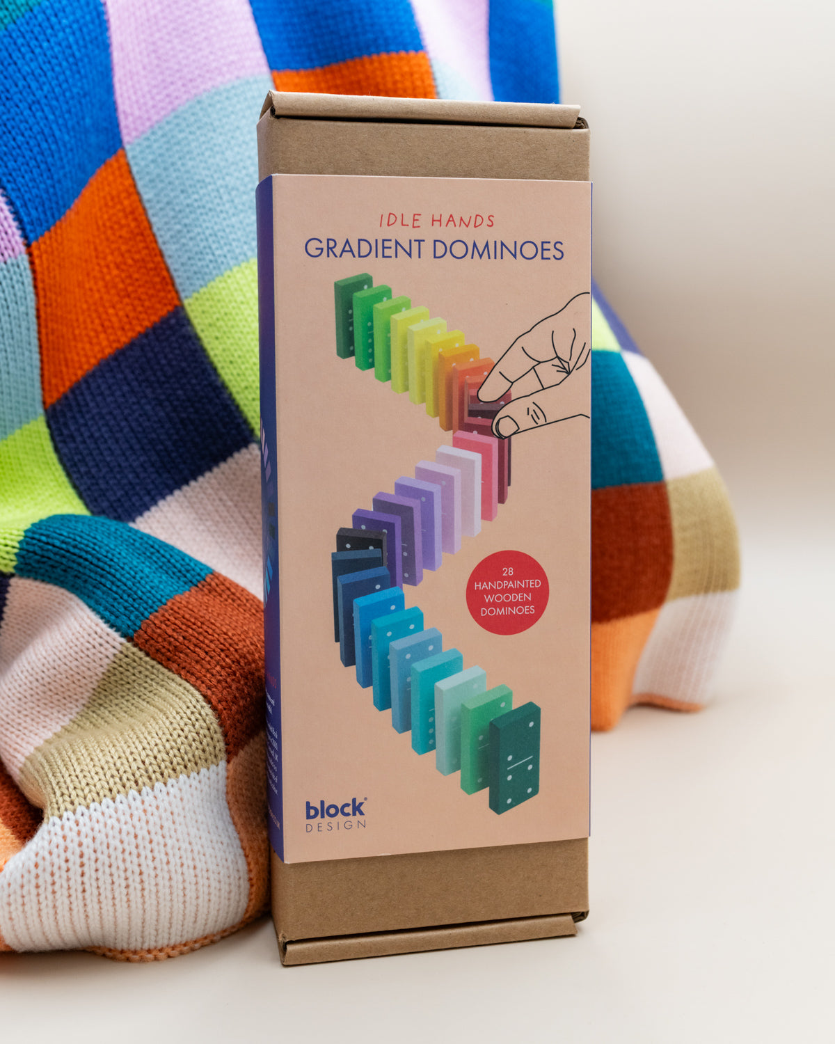 Block Design Gradient Dominoes box standing on a colorful knit blanket