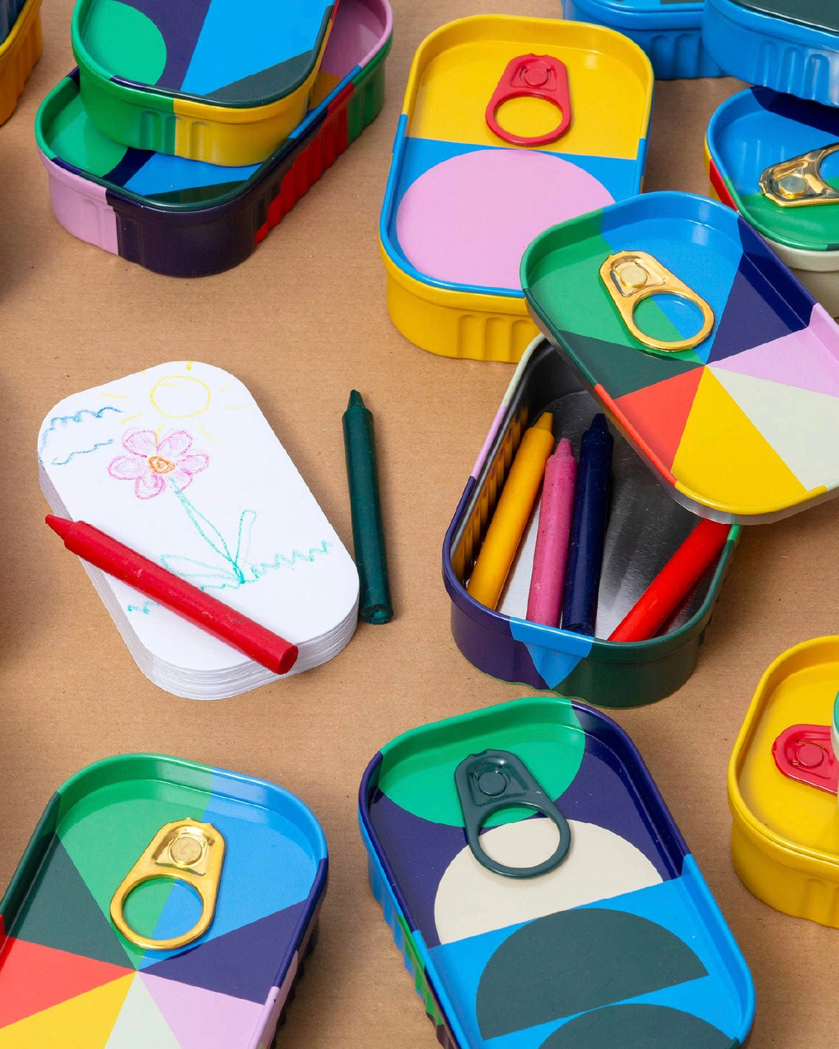 Top Draw tins with pull-tab lids, crayons and a small drawing pad with a child's flower sketch