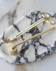 Botanica wick trimmer and bell snuffer in matte brass on an oval marble tray