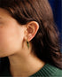 Close-up of an ear wearing a small green and gold CÂPÂ lettuce drop earring