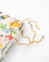 Gold wavy hoop earrings on a book with floral design