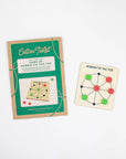 Roman Tic Tac Toe in green kraft packaging beside the wooden game board
