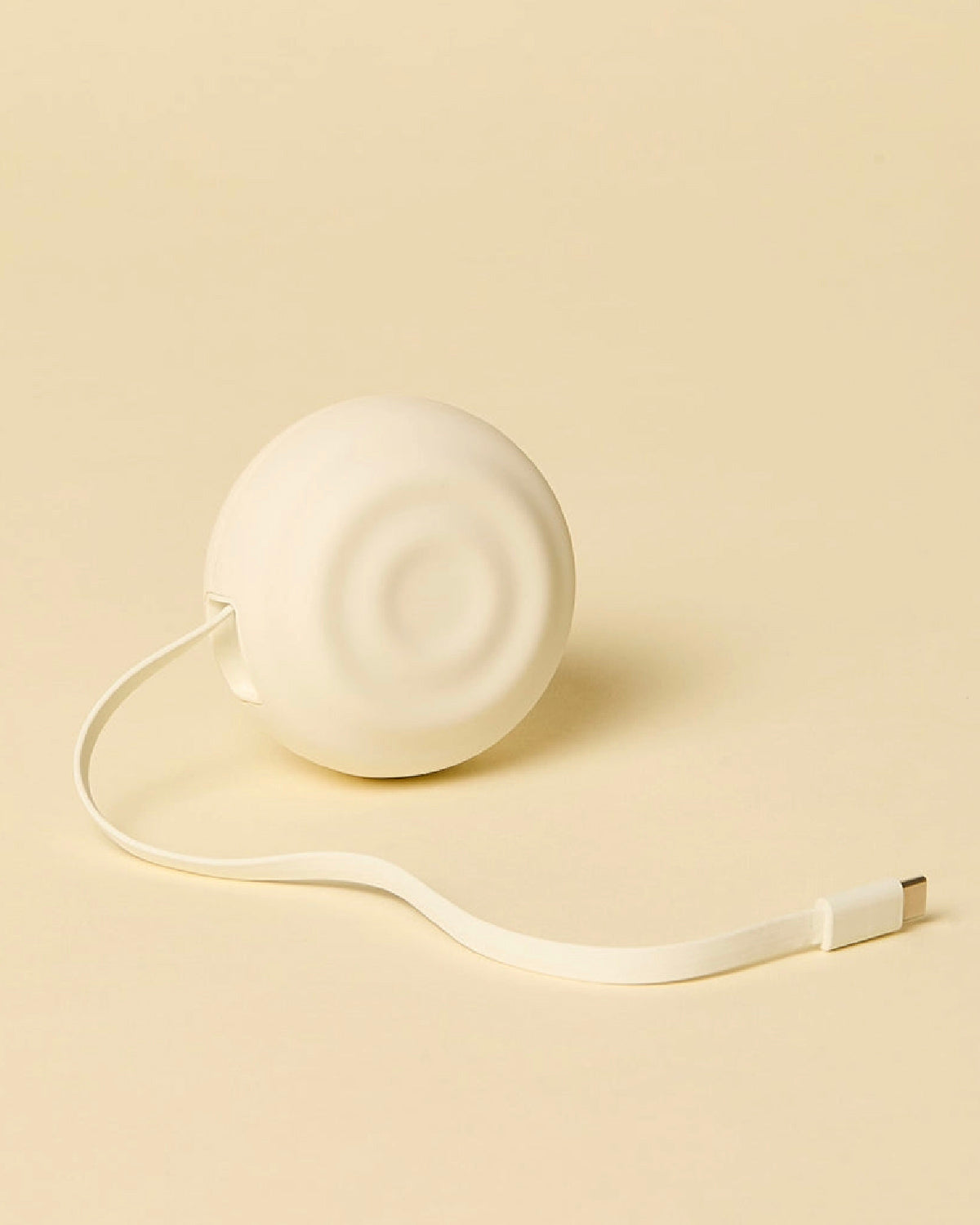 Counterpart white wall charger with its flat USB-C cord pulled out, on a cream background