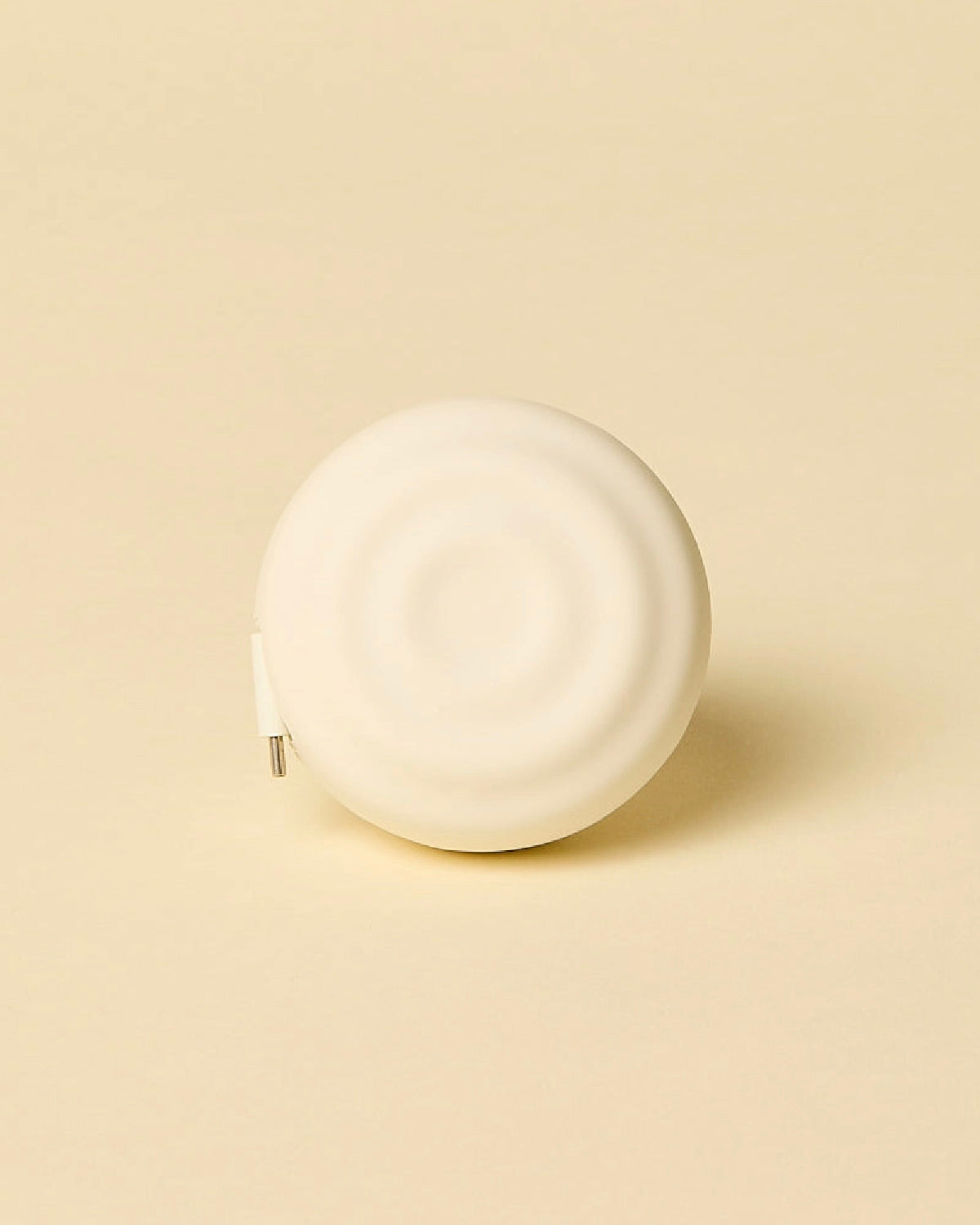 Counterpart USB-C wall charger with the cord fully retracted, showing its round rippled shell